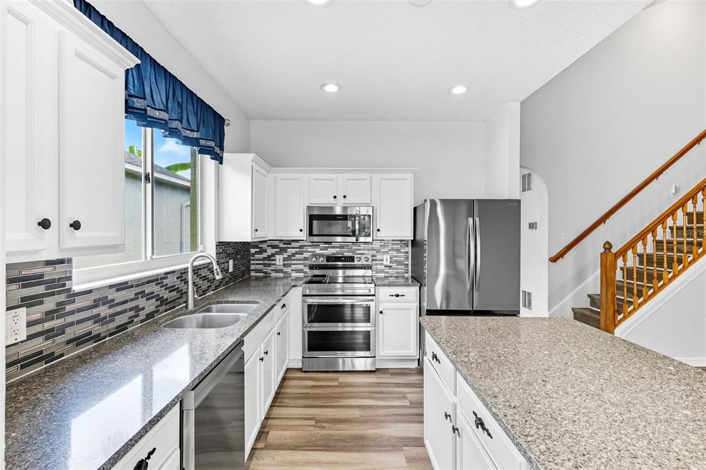 10443 Peppergrass Court Trinity, FL 34655 - Photo 14 of 62 a large kitchen with stainless steel appliances granite countertop a stove a sink and a refrigerator