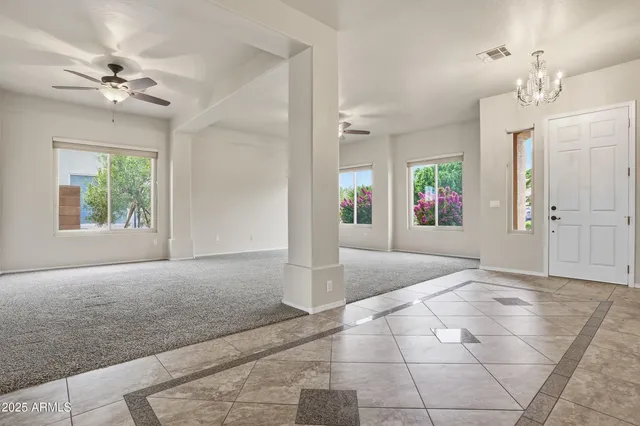 a view of an empty room with a chandelier fan and windows