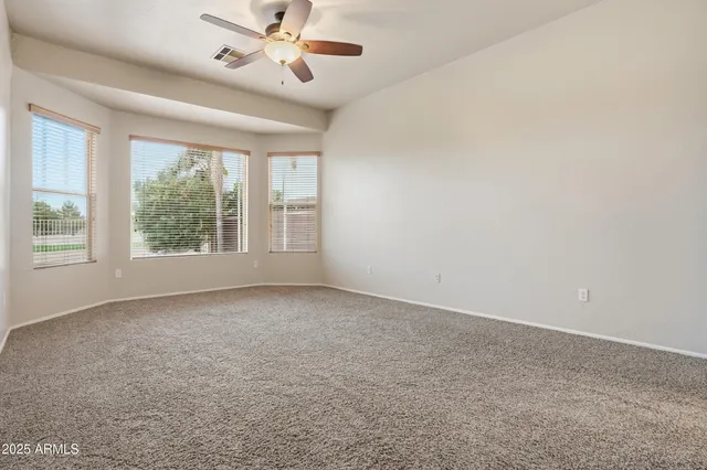 an empty room with windows and ceiling fan