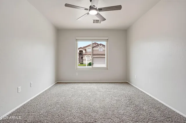 an empty room with windows and fan