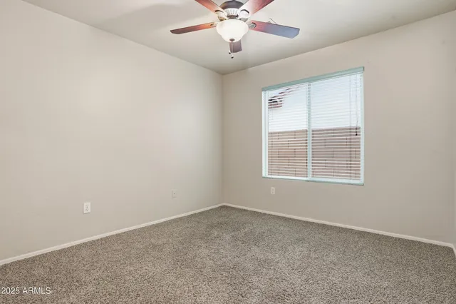 an empty room with a window and a ceiling fan