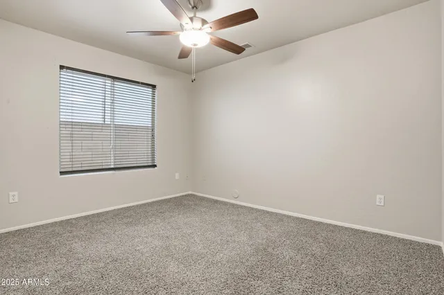 an empty room with a window and a fan