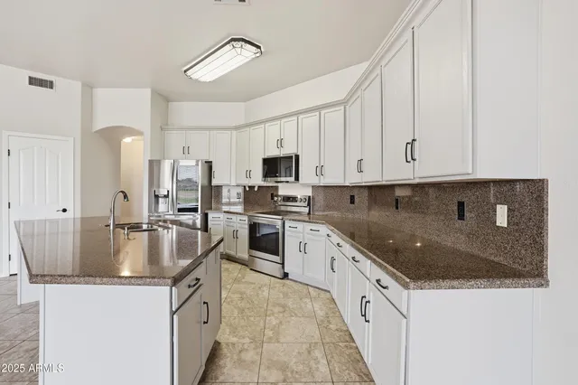 a kitchen with stainless steel appliances granite countertop a sink a stove and a refrigerator
