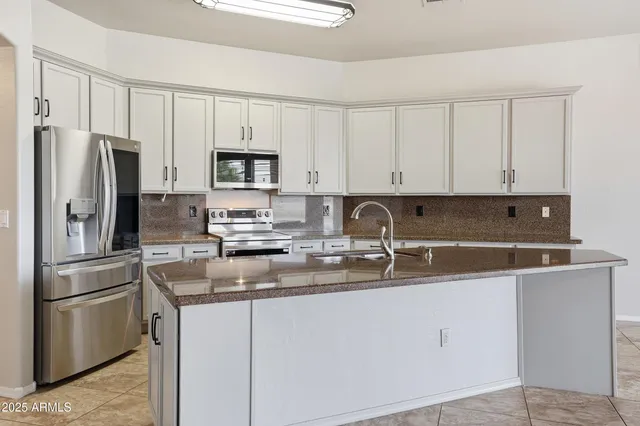 a kitchen with stainless steel appliances granite countertop a refrigerator stove top oven a sink and dishwasher