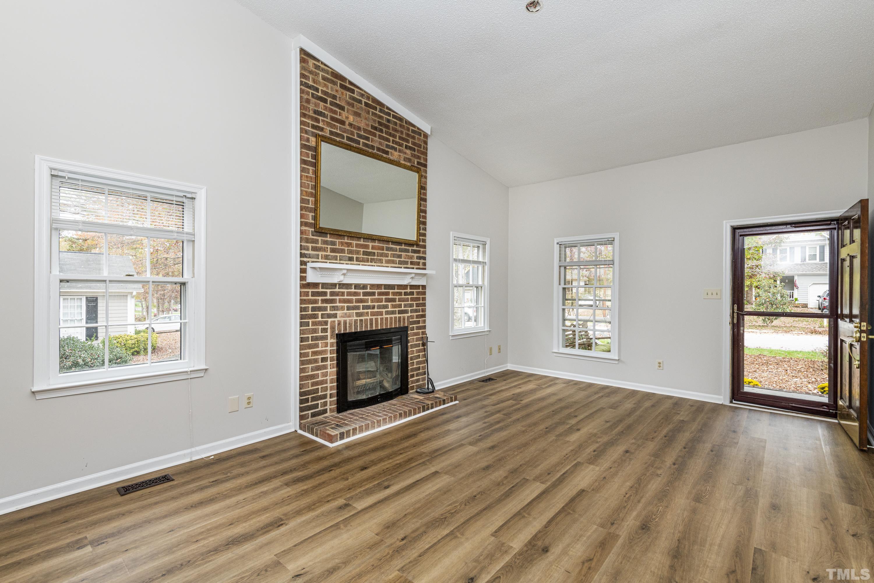 11913 North Exeter Way Raleigh, NC 27613 - Photo 12 of 29 a view of empty room with a fireplace and wooden floor
