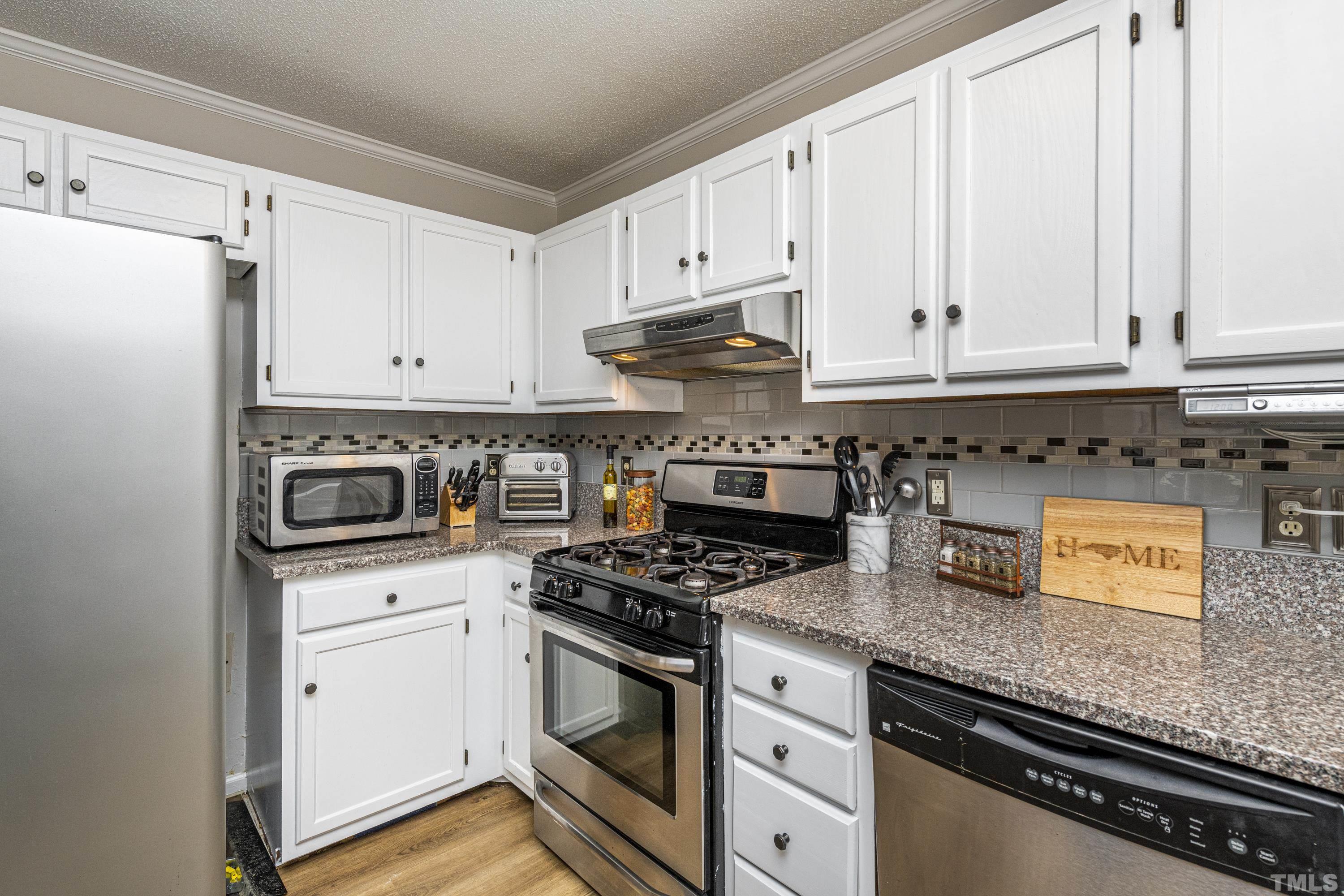 11913 North Exeter Way Raleigh, NC 27613 - Photo 7 of 29 a kitchen with granite countertop white cabinets and appliances