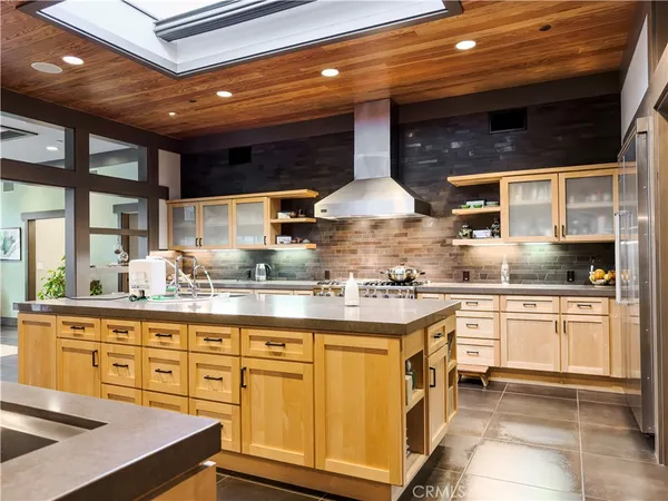 a kitchen with stainless steel appliances granite countertop a sink a stove and a wooden cabinets