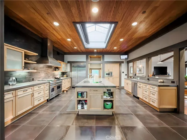 a large white kitchen with stainless steel appliances granite countertop a stove and a sink