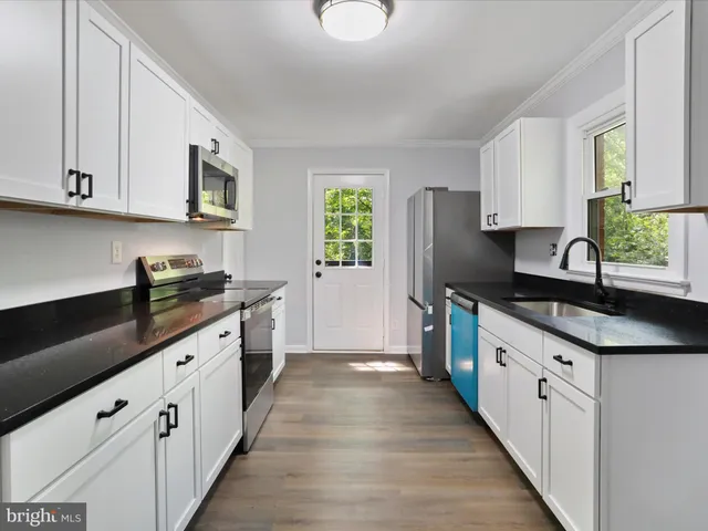 a large kitchen with stainless steel appliances granite countertop a sink dishwasher a stove and a refrigerator