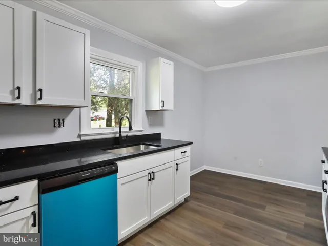 a kitchen with granite countertop white cabinets and sink