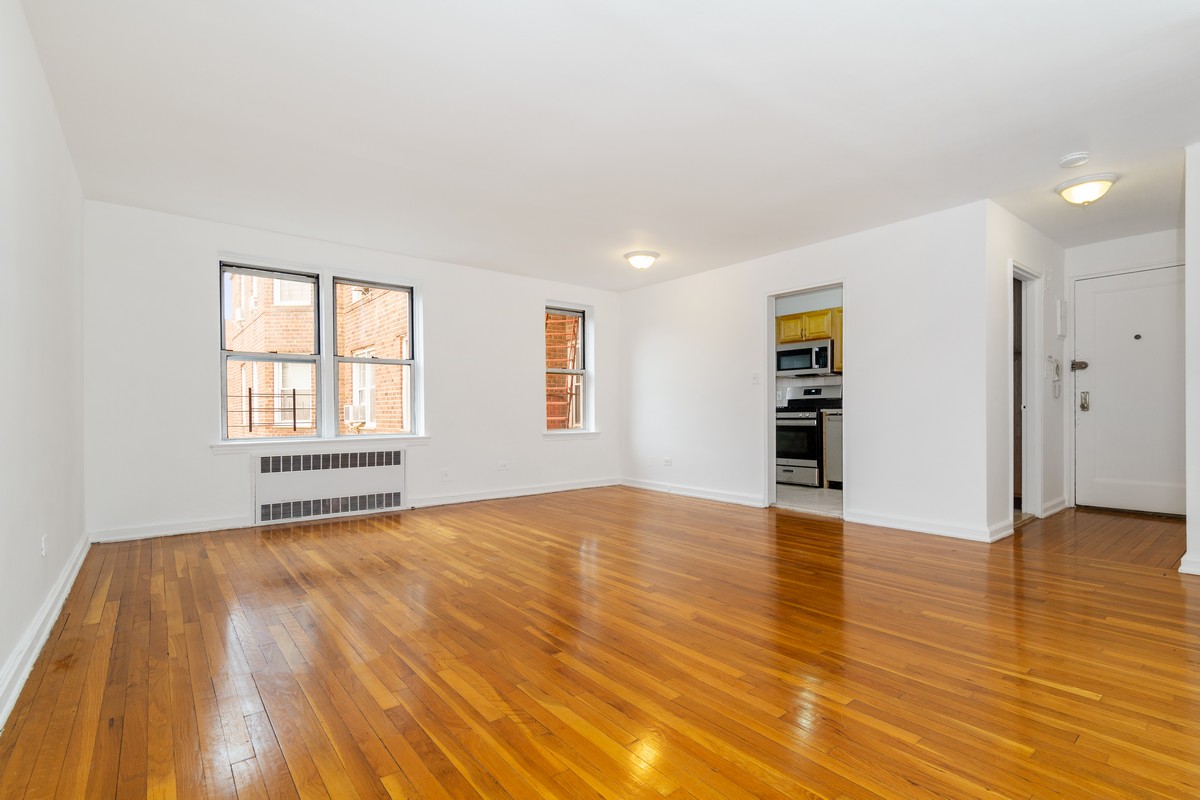 67-07 Yellowstone Boulevard, Unit 5G Queens, NY 11375 - Photo 2 of 7 a view of an empty room with a window and wooden floor