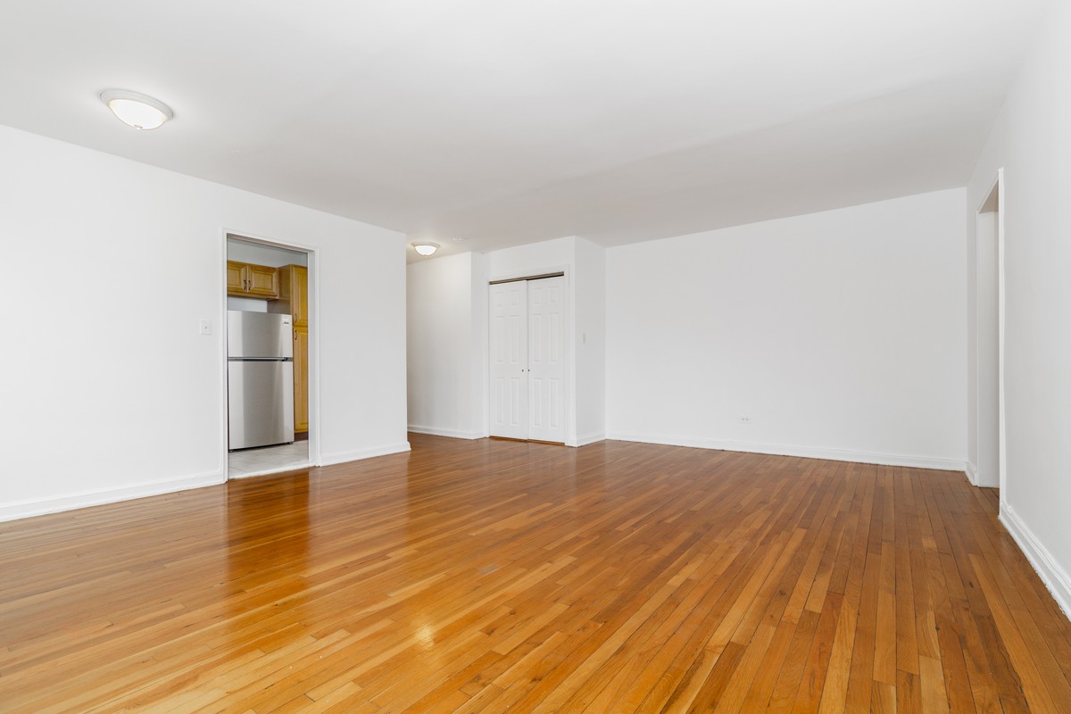 67-07 Yellowstone Boulevard, Unit 5G Queens, NY 11375 - Photo 3 of 7 a view of empty room with wooden floor and kitchen