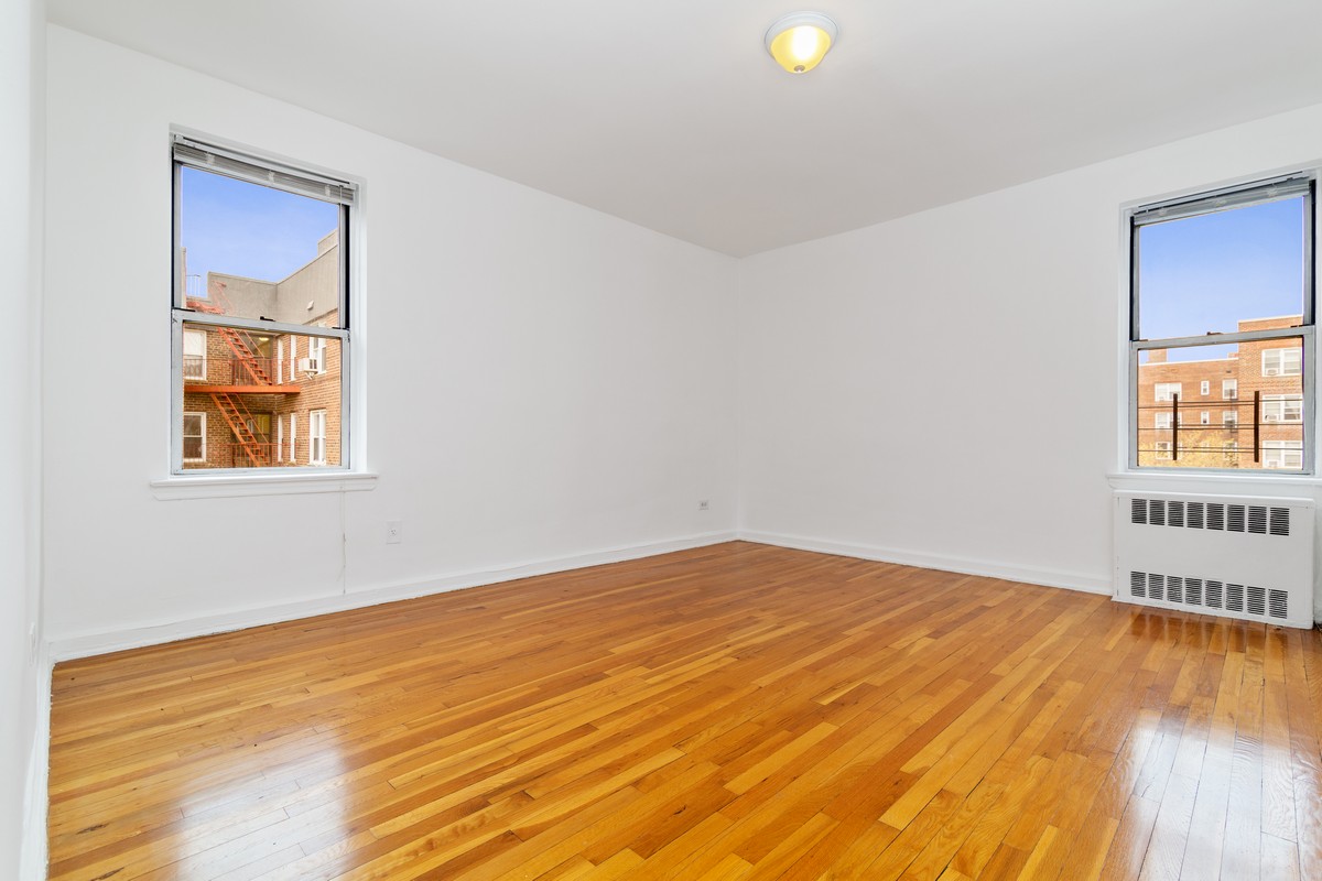 67-07 Yellowstone Boulevard, Unit 5G Queens, NY 11375 - Photo 5 of 7 a view of an empty room with wooden floor and a window