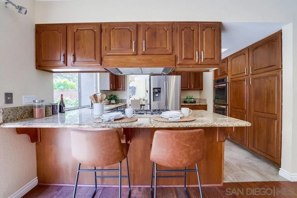 7214 Durango Circle Carlsbad, CA 92011 - Photo 19 of 37 a kitchen with stainless steel appliances granite countertop a table chairs sink and cabinets