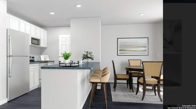 a kitchen with stainless steel appliances granite countertop a table chairs refrigerator and sink