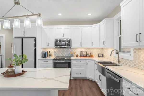 a kitchen with stainless steel appliances kitchen island granite countertop a sink a stove and a wooden floors