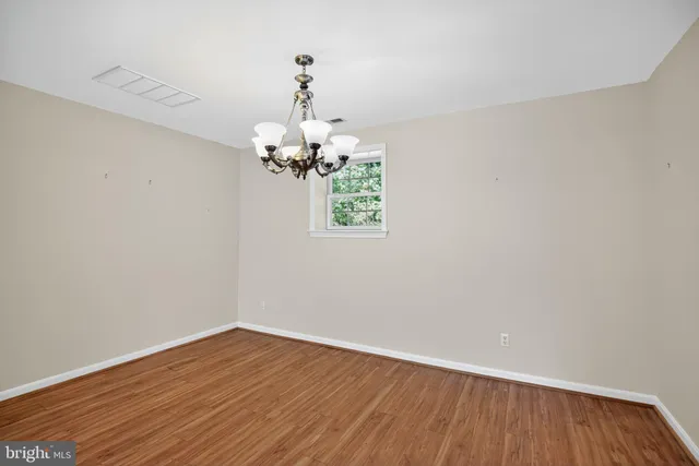 a view of a room with wooden floor chandelier and a window