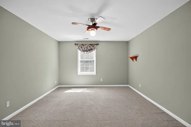 an empty room with a window and a ceiling fan