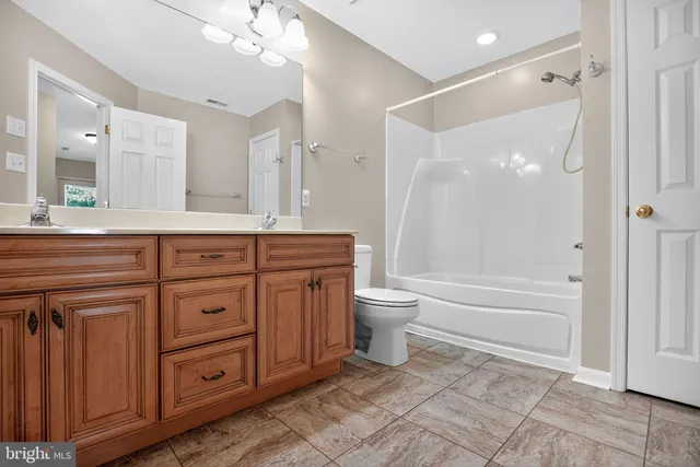 a spacious bathroom with a granite countertop sink a toilet and a bathtub