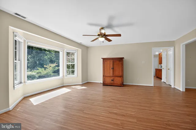 a view of an empty room with window and wooden floor