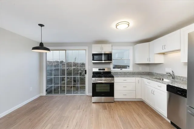 a kitchen with stainless steel appliances granite countertop a stove top oven a sink dishwasher and a refrigerator with wooden floor