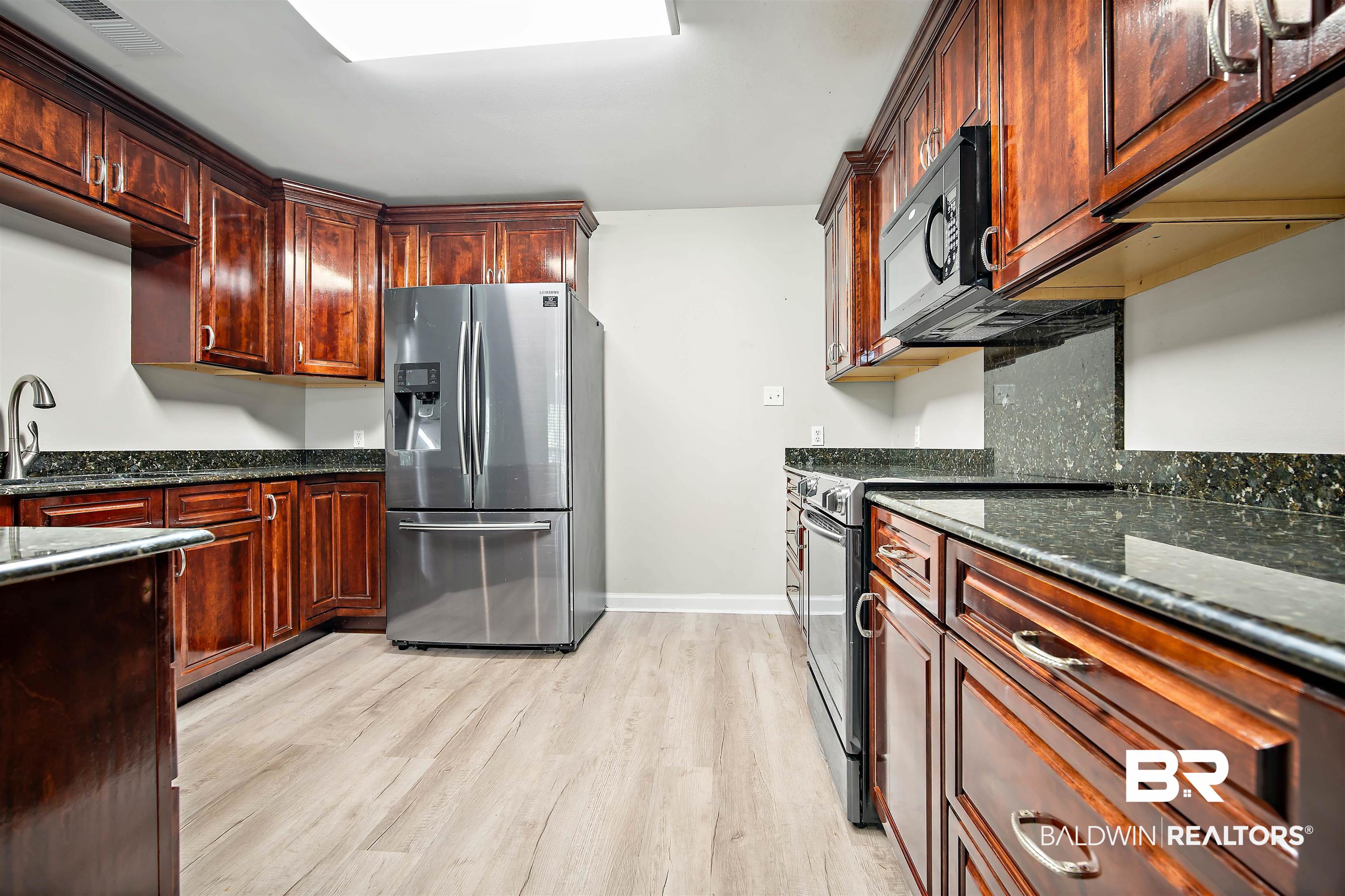 3010 Drag Strip Lane Coden, AL 36523 - Photo 11 of 44 Kitchen featuring sink, appliances with stainless steel finishes, dark stone counters, light hardwood / wood-style flooring, and decorative backsplash