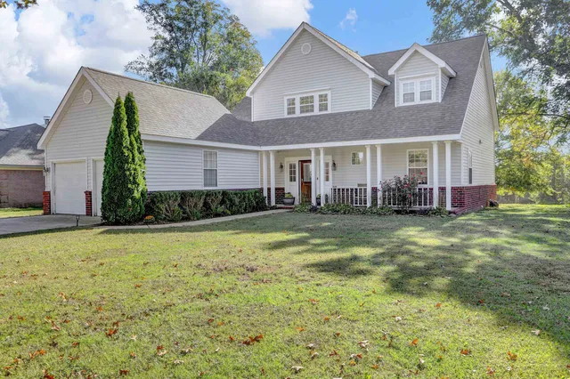 a front view of house with yard and trees in the background