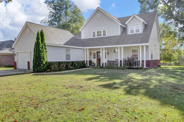 a front view of house with yard and trees in the background