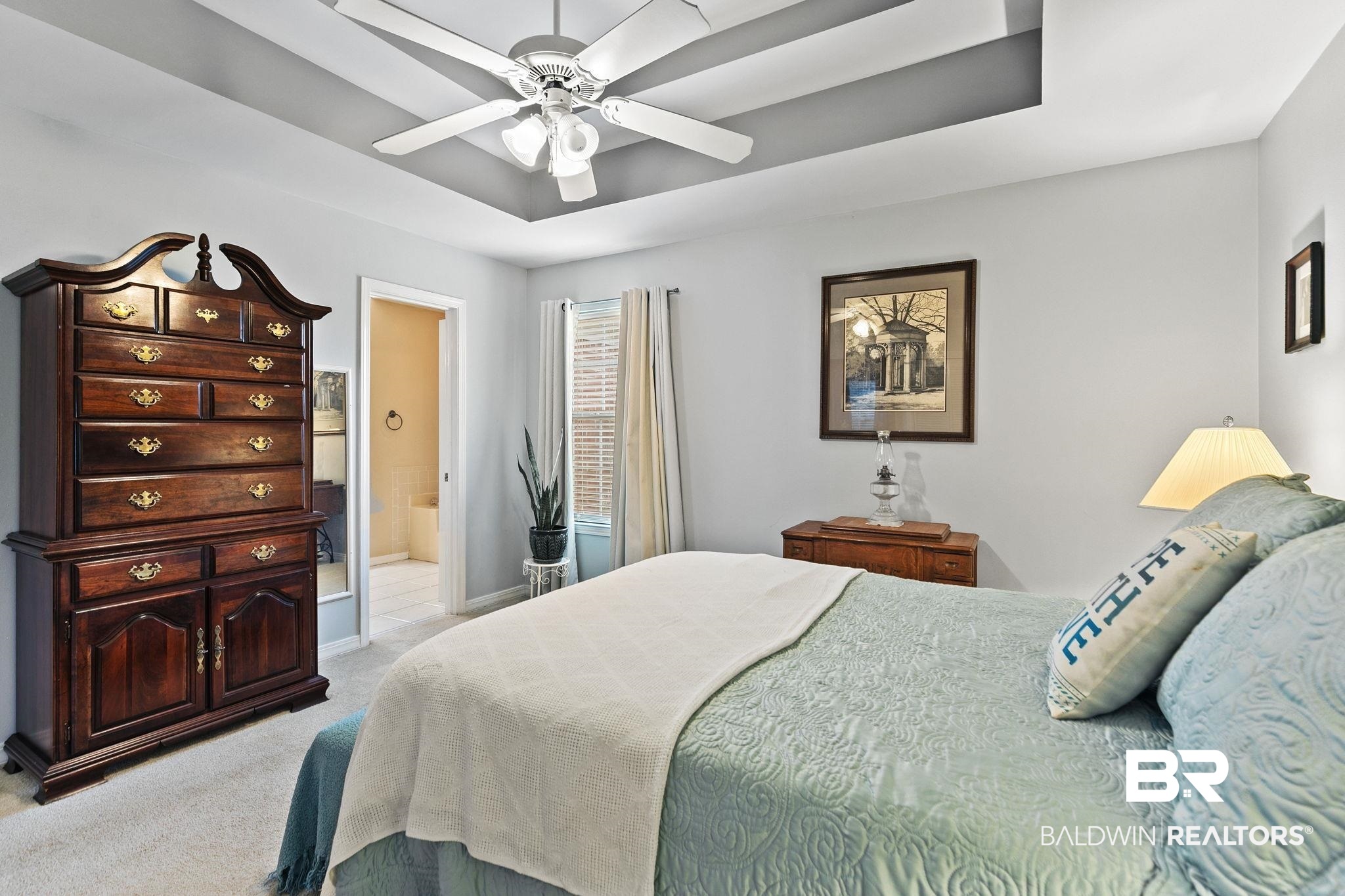 519 Juniper Place Drive Foley, AL 36535 - Photo 21 of 47 Primary bedroom with a raised ceiling, light colored carpet, a ceiling fan, and ensuite bath