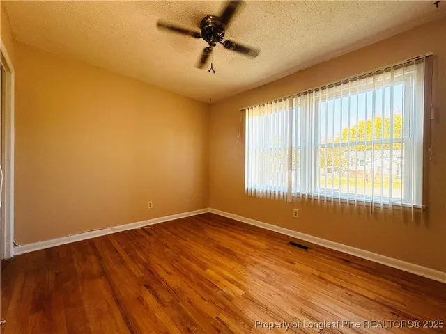 a view of an empty room with a window and a ceiling fan
