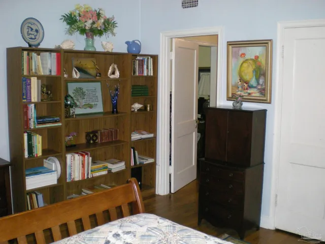 a view of hallway that has closet and wooden floor