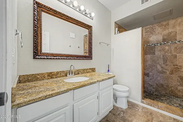 a bathroom with a granite countertop sink mirror vanity and toilet