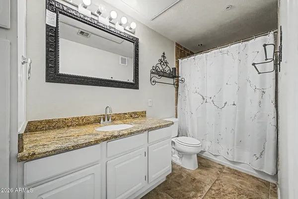 a bathroom with a granite countertop sink a toilet and a mirror