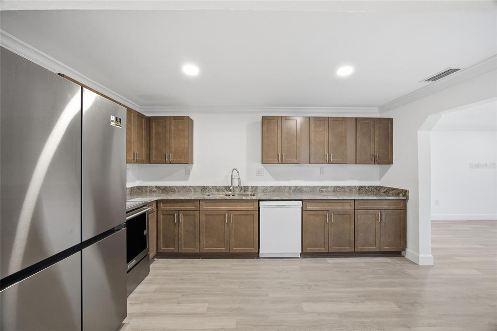 1908 Macomber Avenue Clearwater, FL 33755 - Photo 12 of 24 a large kitchen with granite countertop a sink and dishwasher a stove top oven with wooden floor