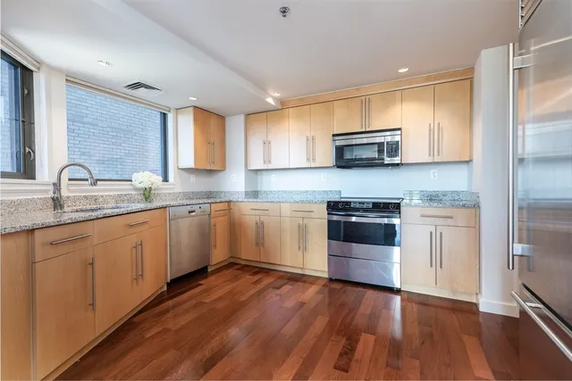 a kitchen with granite countertop wooden floors stainless steel appliances and sink