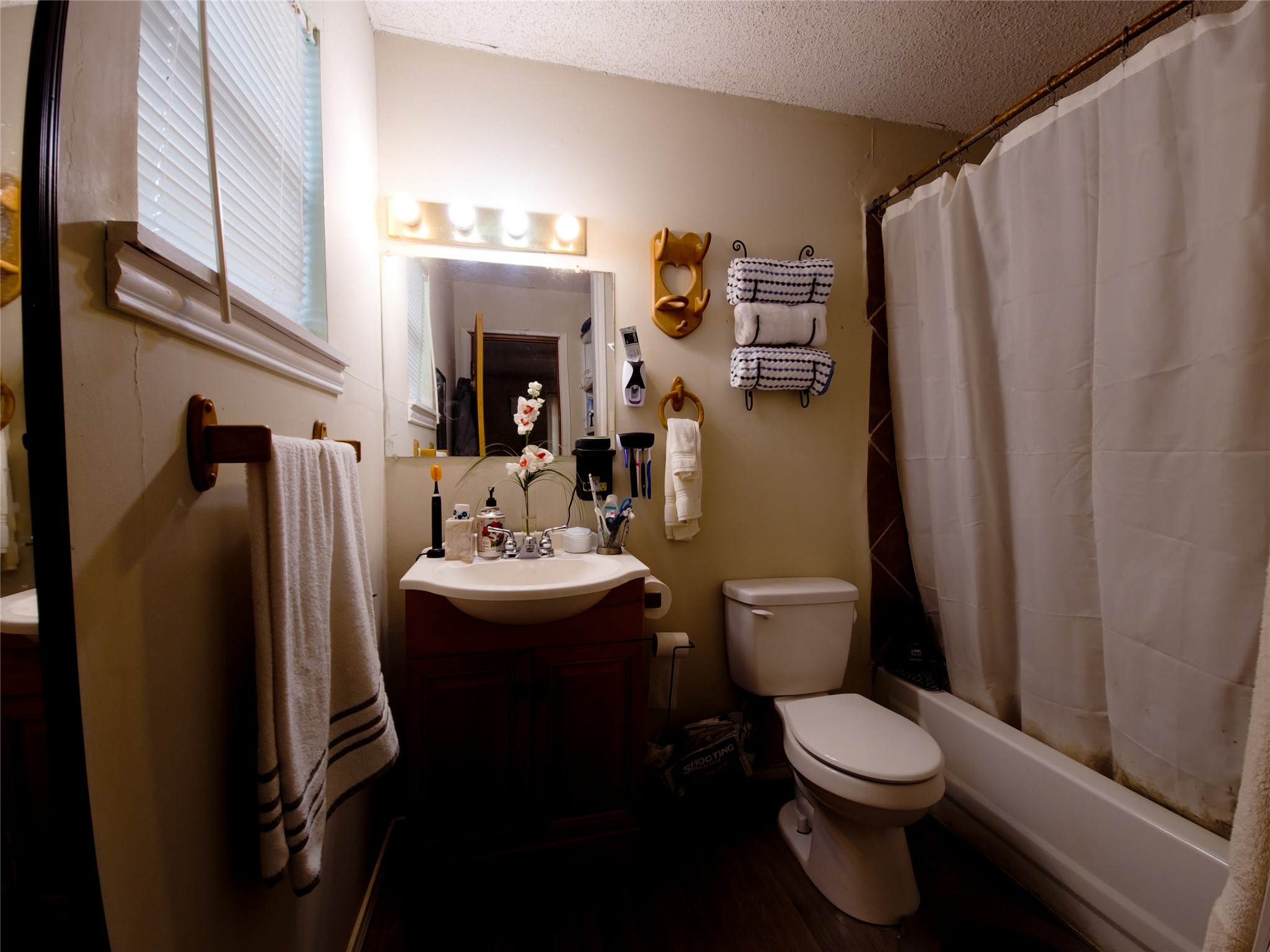 911 Brazos Street Lockhart, TX 78644 - Photo 13 of 22 Full bathroom featuring vanity, a textured ceiling, shower / tub combo with curtain, and dark wood-style floors