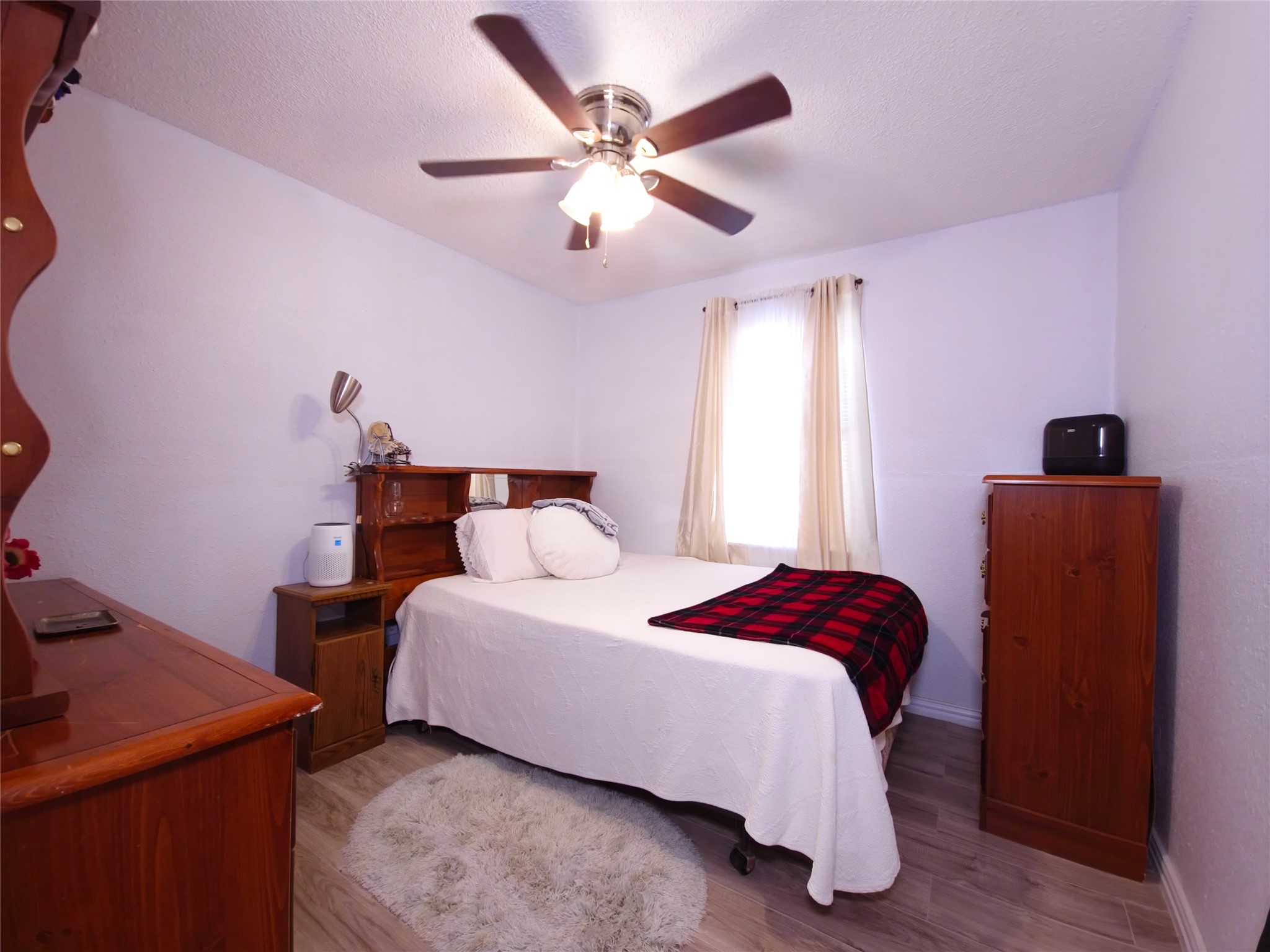 911 Brazos Street Lockhart, TX 78644 - Photo 15 of 22 Bedroom featuring wood finished floors, ceiling fan, and a textured ceiling
