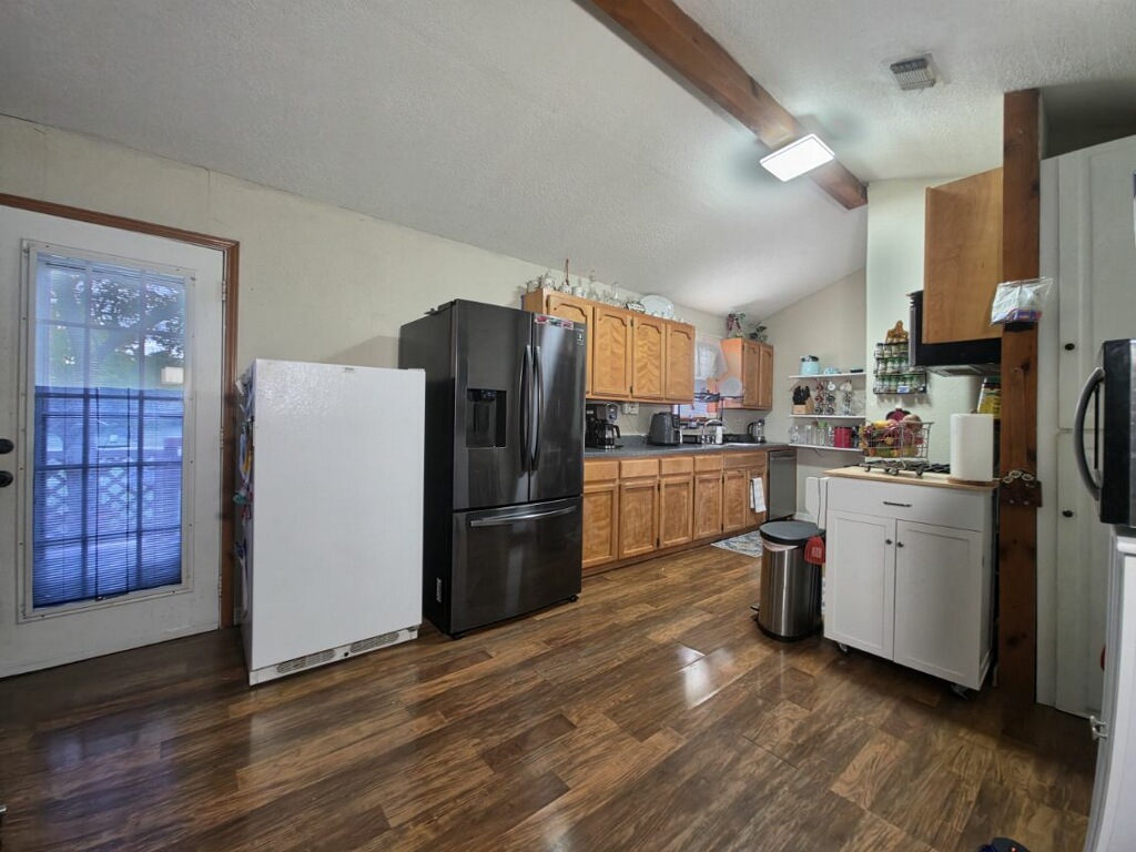 911 Brazos Street Lockhart, TX 78644 - Photo 18 of 22 The property features a kitchen with wood cabinetry, dark countertops, and wood-look flooring