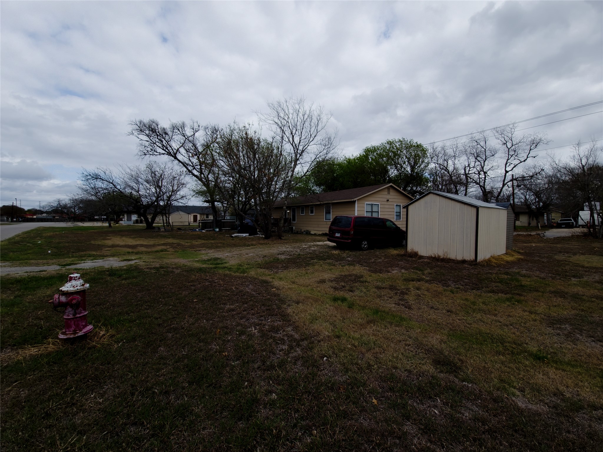 911 Brazos Street Lockhart, TX 78644 - Photo 2 of 22 View of grassy yard with a storage shed and a wooden deck