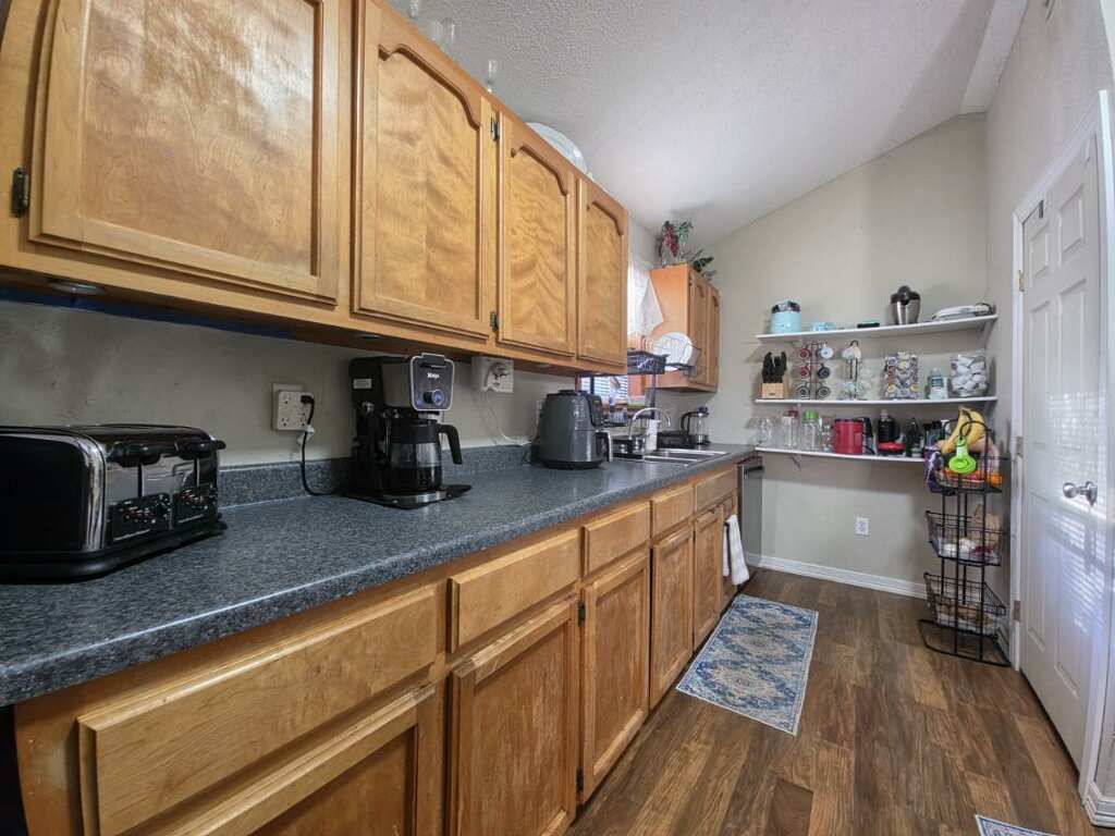911 Brazos Street Lockhart, TX 78644 - Photo 22 of 22 The kitchen features wood cabinetry, dark countertops, and wood-look flooring