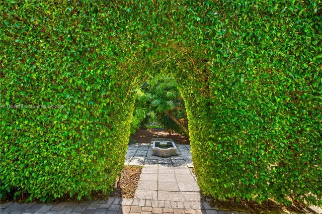 a backyard of a house with table and chairs potted plants and large tree