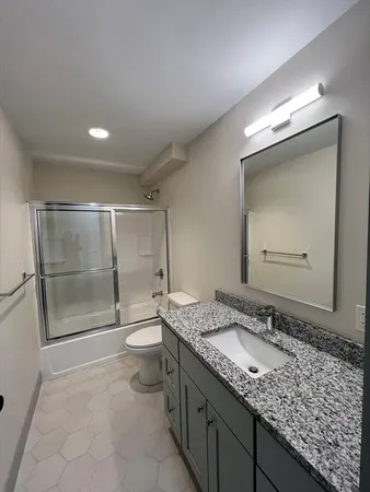 a bathroom with a granite countertop sink a toilet and a shower