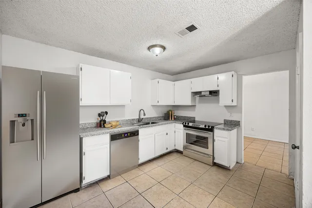 a kitchen with white cabinets and appliances