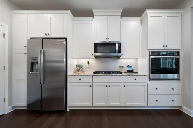 a kitchen with cabinets stainless steel appliances and wooden floor
