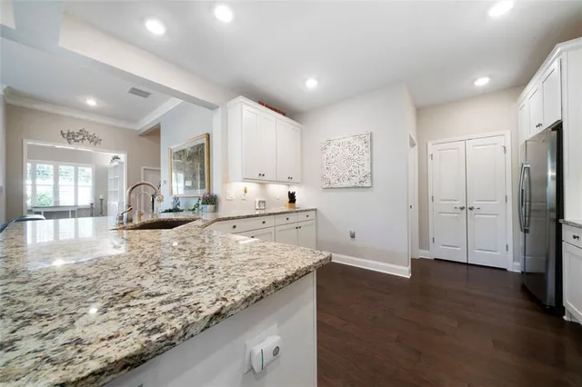 a view of a kitchen with granite countertop refrigerator stove and wooden floor