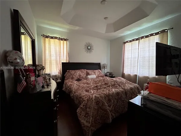 a bedroom with a bed window and a flat screen tv