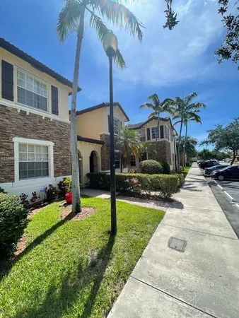 a view of a house with a yard and palm trees