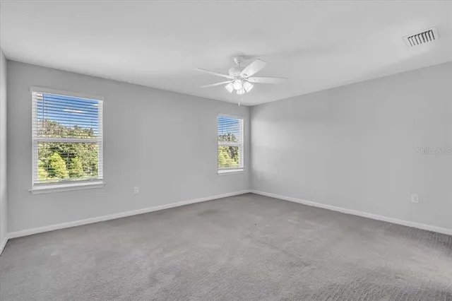 an empty room with windows and ceiling fan