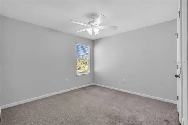 an empty room with a window and a fan