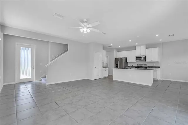 a view of kitchen with kitchen island stainless steel appliances a sink counter top space cabinets and a window